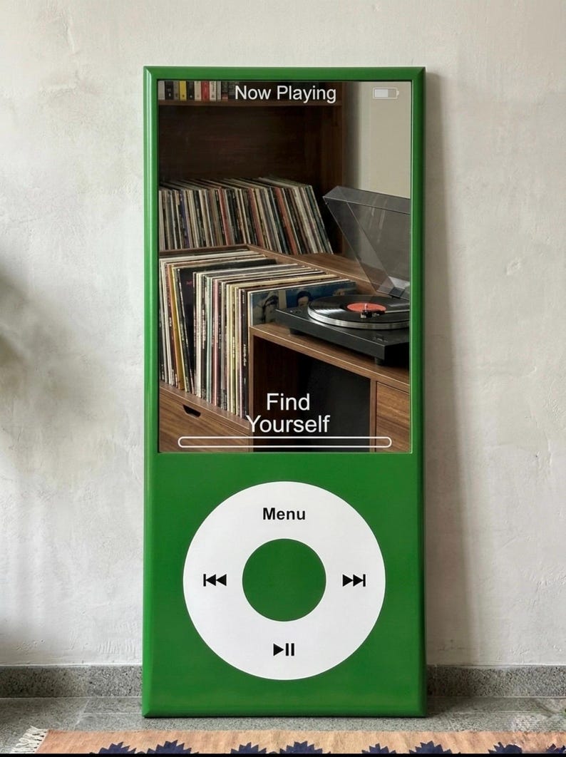 May include: A tall, rectangular green mirror designed to resemble a classic digital music player. The top section features a reflective surface displaying the text Now Playing and Find Yourself. The bottom section has a white circular control interface.
