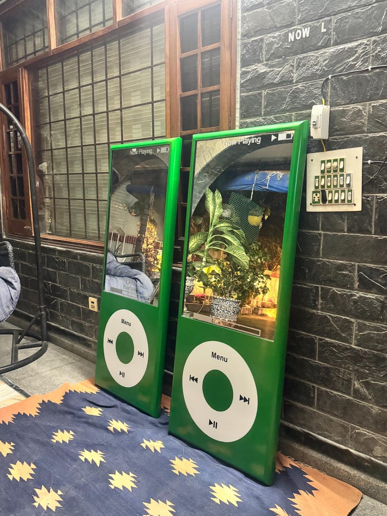 May include: Two tall, rectangular green mirrors designed to resemble classic digital music players. Each mirror features a white circular control interface with a Menu button and playback icons, plus a Now Playing display at the top of the glass.