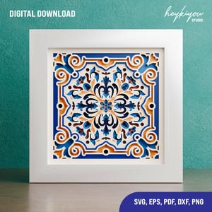 Peut inclure: Une œuvre d'art encadrée en papier découpé avec un motif floral symétrique. L'œuvre présente des découpes complexes dans les tons de bleu, orange et blanc, sur un cadre blanc. Les mots "DIGITAL DOWNLOAD" sont en haut à gauche.