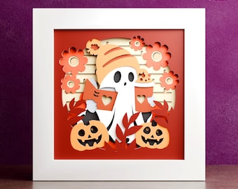 Op de afbeelding: Een gelaagd papieren kunstwerk in een witte lijst, met een vriendelijk spook met een hoed, lezend in een boek en een kopje vasthoudend. Oranje pompoenen en bloemen omringen het spook. De tekst "DIGITALE DOWNLOAD" en bestandsformaten zijn zichtbaar.