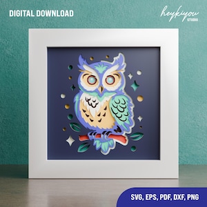 May include: A framed paper cut owl design. The owl is in shades of blue, green, and yellow, perched on a brown branch against a dark blue background. The frame is white, and the words "DIGITAL DOWNLOAD" are at the top left. The bottom right corner has the words "SVG, EPS, PDF, DXF, PNG".