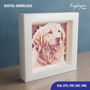 May include: A digital download of a layered paper cut design of a golden retriever dog in a white frame. The dog is looking to the right with its tongue sticking out. The design is in shades of pink and white.
