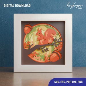 May include: A digital download of a layered paper cut design featuring a red squirrel sitting on a branch with acorns and fall leaves. The design is in a circular frame with a brown background.