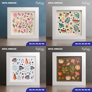 May include: Four framed paper cut art pieces. The top left features pink and yellow flowers. The top right has watermelon and pineapple designs. The bottom left shows mugs and snowflakes. The bottom right has pumpkins and leaves. Each frame is white.