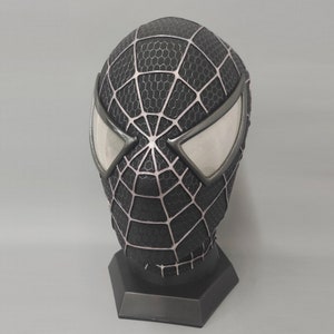 Puede incluir: M&aacute;scara de Spider-Man negra y plateada con un dise&ntilde;o de telara&ntilde;a. La m&aacute;scara tiene un soporte y est&aacute; hecha de un material suave.