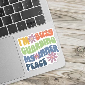 A colorful sticker in a retro font that says I'm busy guarding my inner peace on a laptop