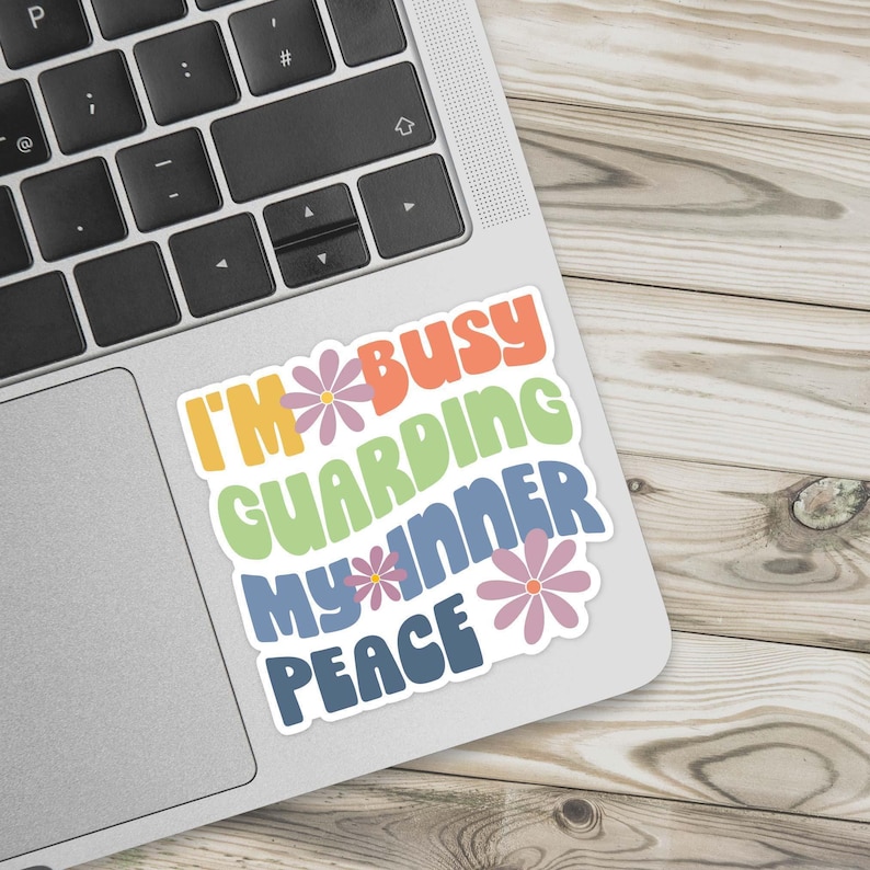 A colorful sticker in a retro font that says I'm busy guarding my inner peace on a laptop