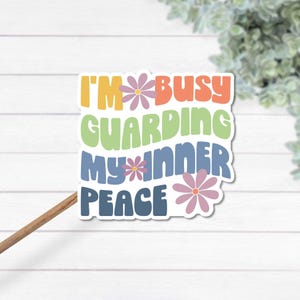 A colorful sticker in a retro font that says I'm busy guarding my inner peace on a stick