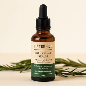 May include: A brown glass bottle of Tinybreeze Tricho Hair Serum with a black dropper. The label includes the text "Advance Hair Growth & Strength Formula" and ingredient percentages. Rosemary sprigs are in the background. The bottle contains 50 ML.
