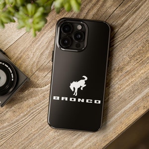 Könnte beinhalten: Schwarze Handyhülle mit einem weißen Ford Bronco Logo und einer weißen Silhouette eines Pferdes. Die Hülle hat eine schwarze Kamera-Erhebung mit drei Objektiven.