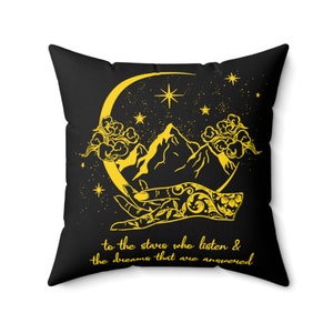 May include: Black throw pillow with a yellow crescent moon, mountains, and a hand with a star design. The text "to the stars who listen & the dreams that are answered" is printed in yellow.