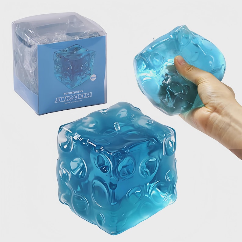 May include: A translucent blue stress ball in a cube shape, resembling cheese. The image shows the stress ball in its packaging and being held. The box features the text "FUFUSQUISHY JUMBO CHEESE".