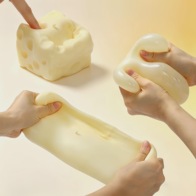 May include: A light yellow, cheese-shaped stress ball with holes is being pressed by a finger. Two other stress balls are being stretched and squeezed by hands. The stress balls are a soft, pliable material.