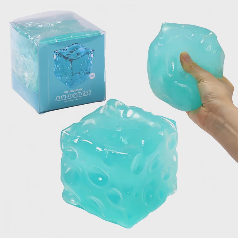 May include: A light blue, cube-shaped stress ball with a textured surface, resembling a block of cheese. The packaging reads "FUFUSQUISHY JUMBO CHEESE". One is held in a hand, and another is on display.