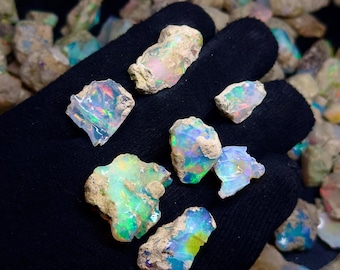 Könnte beinhalten: Eine Sammlung von rohen Opal-Steinen in verschiedenen Blautönen, Grüntönen und Weißtönen. Die Steine sind in einer dunkelgrauen Matrix eingebettet und haben eine natürliche, unpolierte Oberfläche.