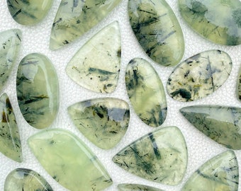 May include: A collection of green and black gemstone cabochons with a variety of shapes and sizes. The stones have a translucent appearance with a swirling pattern of black inclusions.