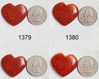 May include: Four red heart-shaped stones with a sparkly finish. Each stone is next to a US quarter for size comparison.