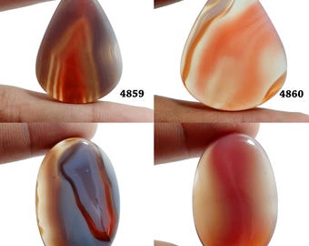 Könnte beinhalten: Vier Achat-Cabochons in verschiedenen Formen und Farben, darunter Rot, Orange, Braun und Weiß. Die Cabochons werden auf einer Hand gezeigt, wobei die Produktnummern 4859, 4860, 4861 und 4862 sichtbar sind.