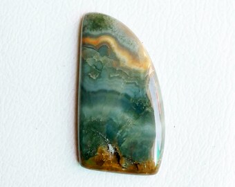 May include: A green, brown, and white cabochon gemstone with a smooth, polished surface. The gemstone has a unique, swirling pattern.