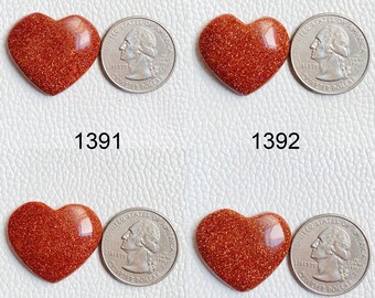 May include: Four heart-shaped red sandstone cabochons, each about the size of a US quarter. The stones have a sparkly, glittery texture.