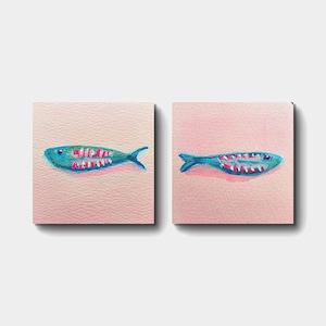 Könnte beinhalten: Zwei quadratische Kunstdrucke mit einem skurrilen Fischdesign. Jeder Fisch ist türkis mit rosa und weißen Details auf einem weichen rosa Hintergrund gemalt. Das Kunstwerk ist im Aquarellstil gehalten, ideal für die Küstendekoration.