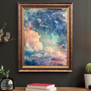 Op de afbeelding: Een ingelijste kunstdruk met een dromerige, hemelse sc&egrave;ne. Het kunstwerk toont een levendige mix van kleuren, waaronder roze, blauw en wit, die wolken en een sterrenhemel uitbeelden. De lijst heeft een warme, sierlijke goudkleur.
