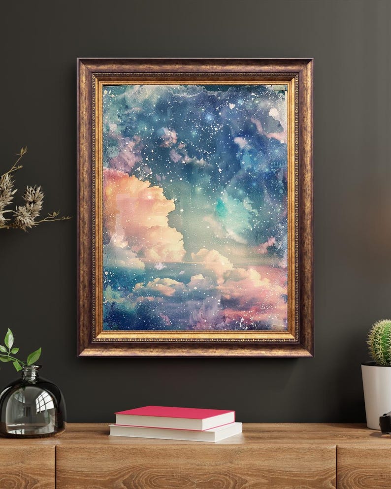 Op de afbeelding: Een ingelijste kunstdruk met een dromerige, hemelse sc&egrave;ne. Het kunstwerk toont een levendige mix van kleuren, waaronder roze, blauw en wit, die wolken en een sterrenhemel uitbeelden. De lijst heeft een warme, sierlijke goudkleur.
