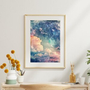 Op de afbeelding: Een ingelijste kunstdruk met een aquarel schilderij van een hemelse sc&egrave;ne. Het kunstwerk toont pluizige roze en witte wolken tegen een achtergrond van een sterrenhemel, diepblauwe lucht. De print zit in een licht houten frame.