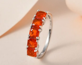 May include: A silver ring with a row of six orange square-shaped gemstones.