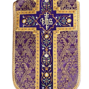 May include: A purple liturgical vestment with gold floral brocade and a central cross design. The cross features the letters IHS and floral embroidery in white, green, and yellow. Gold trim borders the vestment.