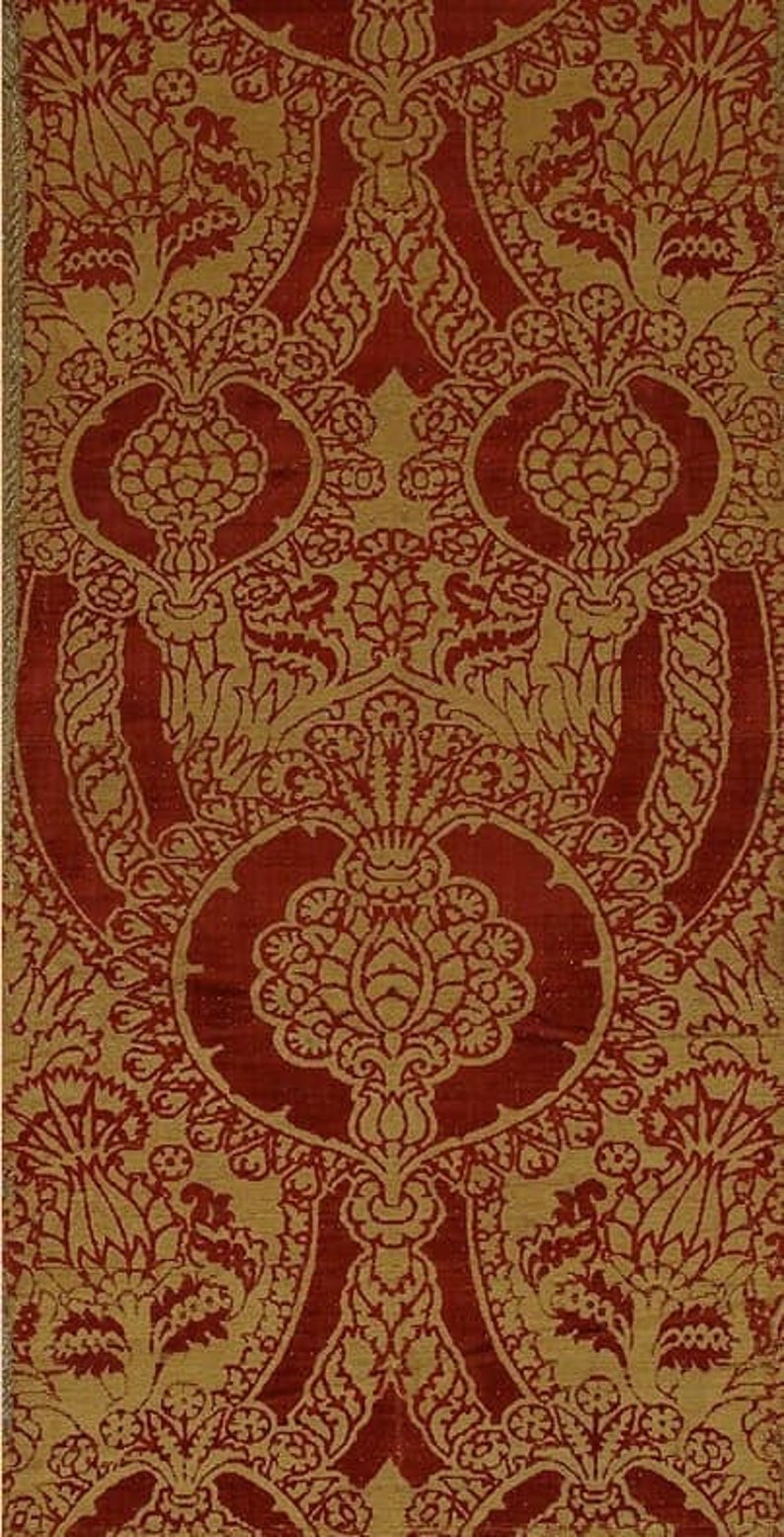 K&ouml;nnte beinhalten: Ein roter und goldener Stoff mit einem sich wiederholenden Muster aus stilisierten Blumen und Bl&auml;ttern. Der Stoff hat eine reiche, strukturierte Optik und Haptik.