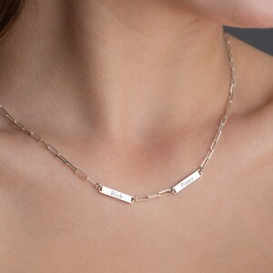 May include: A silver chain necklace with two rectangular pendants. The pendants are engraved with the names "Poppy" and "Rick".