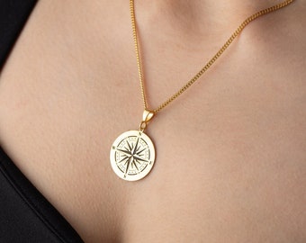 May include: A gold chain necklace with a compass pendant. The compass is round and has a detailed design.