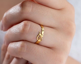 Op de afbeelding: Een gouden ring met de naam "Emma" in cursief.