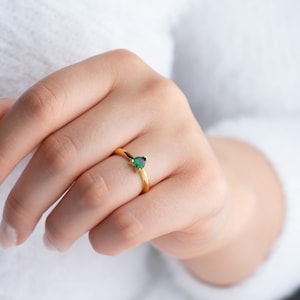 May include: A gold ring with a small, teardrop-shaped green gemstone.