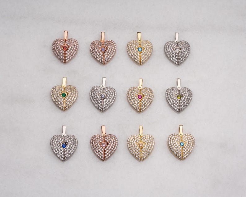 Peut inclure: Une collection de pendentifs en forme de c&oelig;ur, chacun orn&eacute; d'une pierre pr&eacute;cieuse de couleur diff&eacute;rente. Les pendentifs sont incrust&eacute;s de petites pierres claires et pr&eacute;sentent un design articul&eacute;. Les finitions m&eacute;talliques incluent l'or, l'argent et l'or rose.