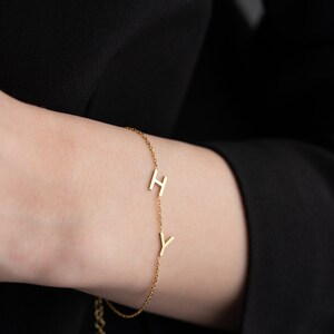 Puede incluir: Un brazalete de cadena dorada con dos dijes de letras, una 'H' y una 'Y'.