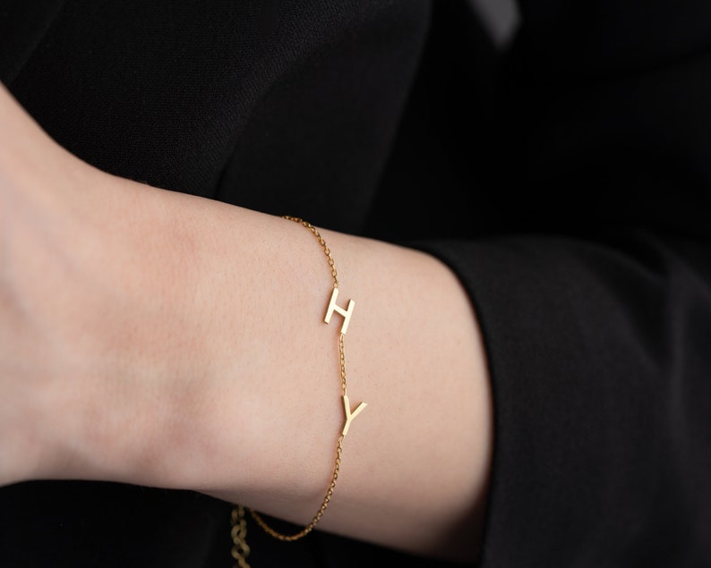 Puede incluir: Un brazalete de cadena dorada con dos dijes de letras, una 'H' y una 'Y'.