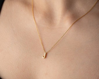 May include: A gold chain necklace with a small letter J pendant.