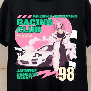 May include: Black t-shirt featuring a graphic design with a racing theme. The design includes the words "Racing Club" and "Japanese Domestic Market," along with a stylized illustration of a car and a woman. The number "98" is also prominently displayed.