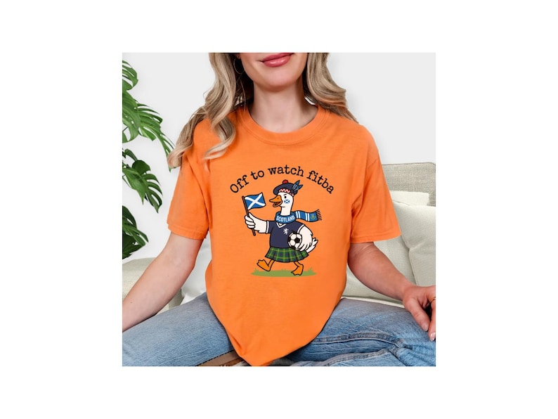 Orange t-shirt lifestyle mockup worn by a woman, featuring a Scottish goose soccer supporter graphic with “Off to watch fitba” text and Scotland details.