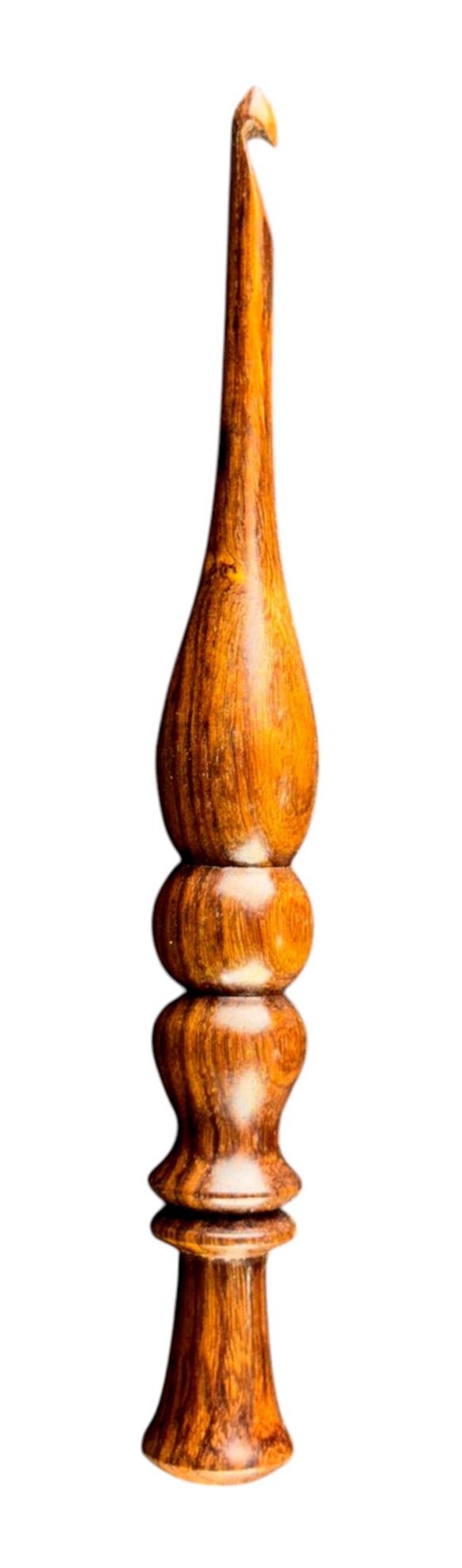 May include: A handcrafted wooden crochet hook with a polished finish. The hook features a curved head and a decorative handle with a bulbous design. The wood grain is visible, showcasing the natural color variations.