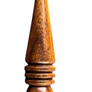 May include: A handcrafted wooden crochet hook with a curved hook end. The hook features a detailed, ergonomic design with a conical midsection and a rounded base, all crafted from warm-toned wood.