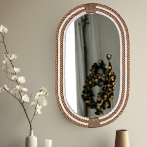 May include: Oval mirror with a brown and white rope frame. The rope is woven in a striped pattern.