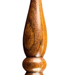 May include: A handcrafted wooden crochet hook with a polished finish. The hook features a curved end for catching yarn and a detailed, ergonomic handle. The wood grain is visible, showcasing the natural beauty of the material.