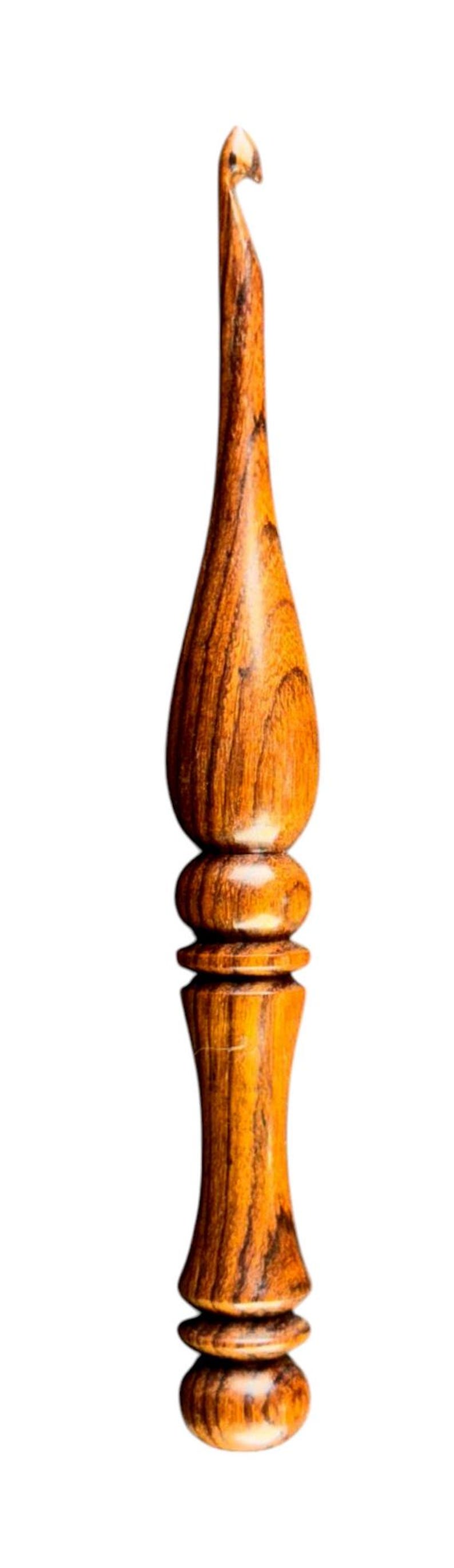 May include: A handcrafted wooden crochet hook with a polished finish. The hook features a rounded handle with a series of decorative rings and a tapered, curved hook end. The wood grain is visible, showcasing the natural color variations.