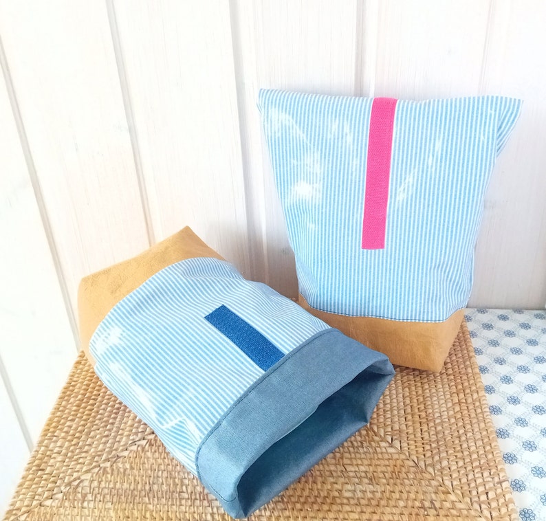 May include: Two striped fabric storage bags with brown leather trim. One bag has a pink stripe and the other has a blue stripe.