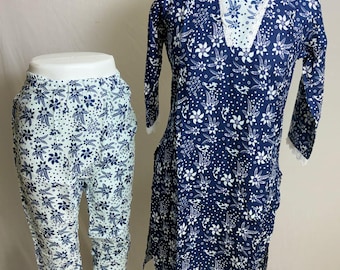 May include: A two-piece pajama set featuring a navy blue tunic and capri pants. The tunic has a white floral pattern and lace trim. The capri pants are light blue with a navy floral pattern. Both pieces are displayed on mannequins.