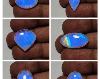 May include: Six iridescent moonstone cabochons in various shapes and sizes, including oval, pear, and heart shapes. The stones are a milky white color with a blue and green iridescent sheen.
