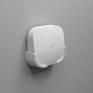 Pode incluir: Um roteador Wi-Fi eero branco, montado em uma parede cinza. O roteador tem formato quadrado com cantos arredondados e o nome da marca "eero" é impresso na frente. Projetado para montagem na parede.